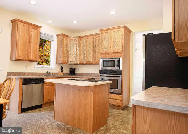 a kitchen with stainless steel appliances granite countertop a sink stove refrigerator and cabinets