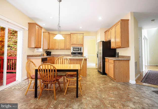 a kitchen with granite countertop a table chairs microwave and refrigerator