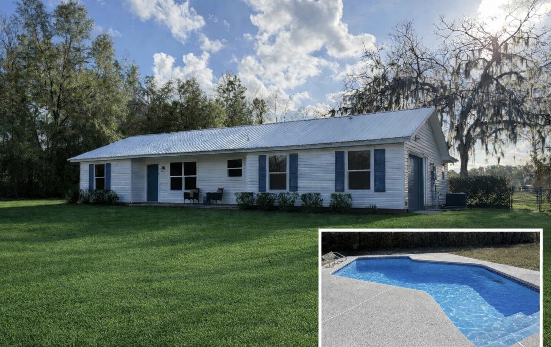Back of house featuring an outdoor pool, a yard, a metal roof, and a patio