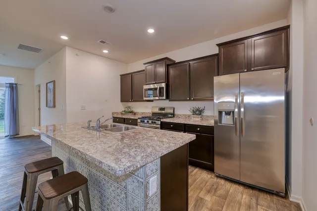 a kitchen with kitchen island a counter space a sink appliances and cabinets
