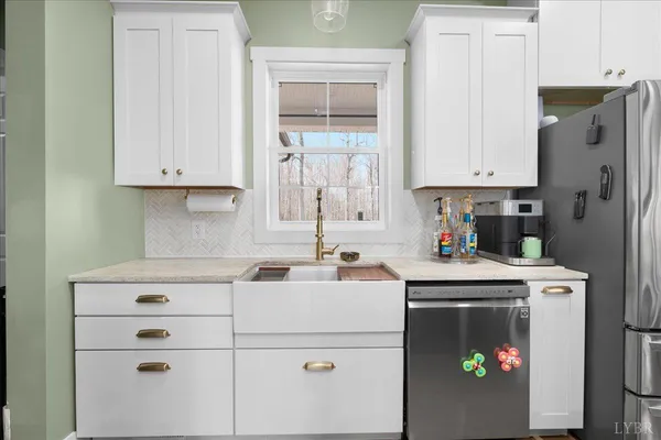 a kitchen with stainless steel appliances white cabinets sink and a refrigerator