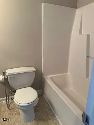 a white toilet sitting next to a bath tub
