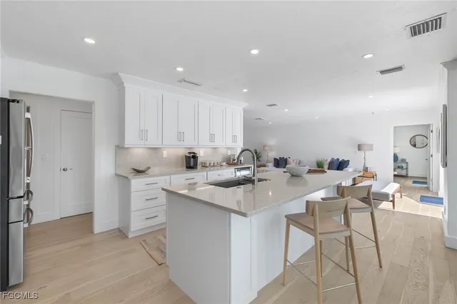 a kitchen with stainless steel appliances kitchen island granite countertop a sink a stove a refrigerator cabinets and chairs