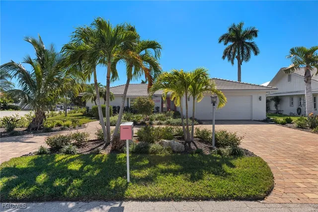 a view of a house with a yard and palm trees