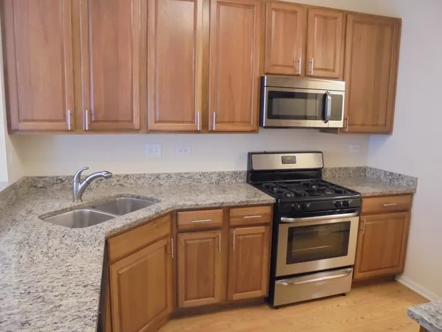 a kitchen with stainless steel appliances granite countertop a stove a sink and a microwave