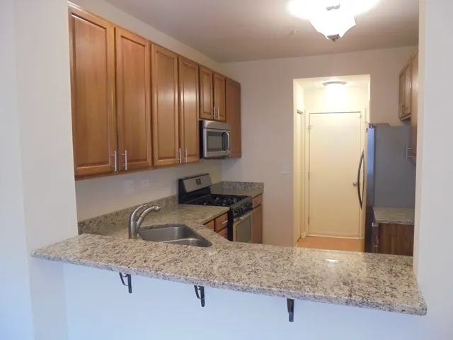 a kitchen with granite countertop stainless steel appliances a sink stove and microwave