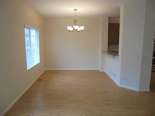 an empty room with chandelier fan and windows