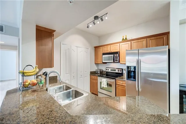 a kitchen with kitchen island granite countertop a sink stove and refrigerator