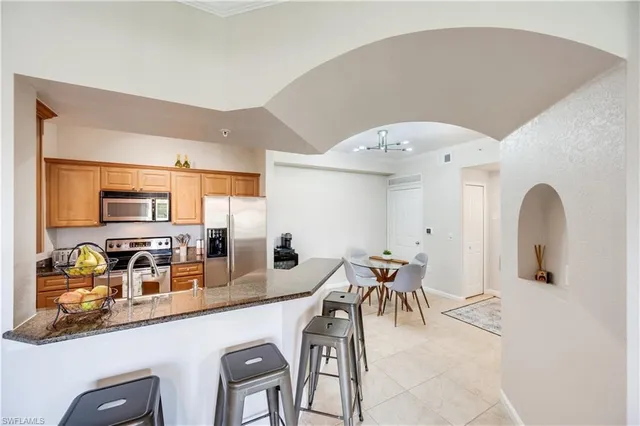 a dining hall with stainless steel appliances a dining table and chairs with kitchen island