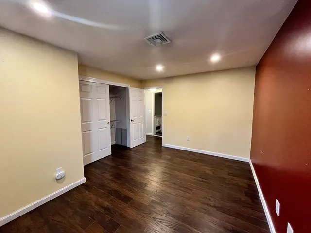 an empty room with wooden floor and entrance