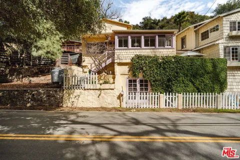 a view of a house with a small yard and wooden fence