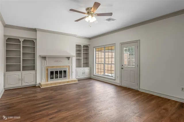 a view of a livingroom with a fireplace a ceiling fan and windows