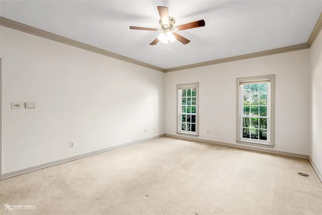 an empty room with windows and ceiling fan
