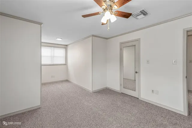 an empty room with chandelier fan and windows