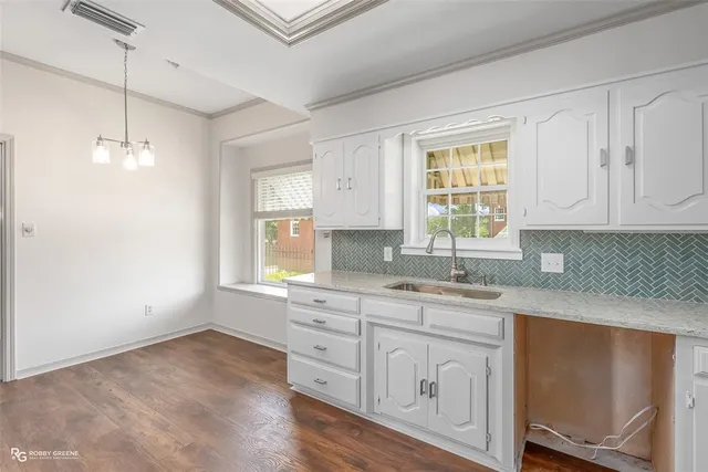 a kitchen with white cabinets and window