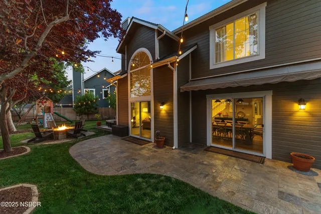 a view of a house with brick walls and a yard with a large tree