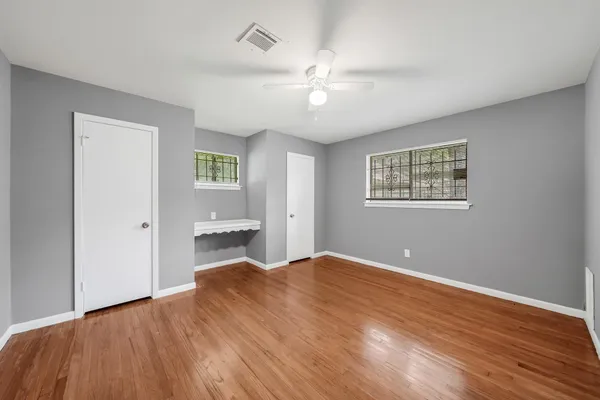 a bedroom with wooden floor and a ceiling fan