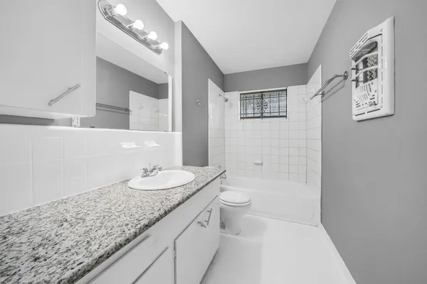 a bathroom with a granite countertop sink a toilet and a mirror