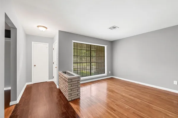 a view of an empty room with wooden floor and a window