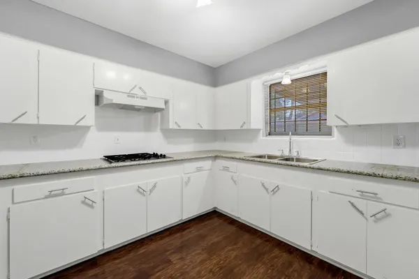 a kitchen with granite countertop white cabinets and sink