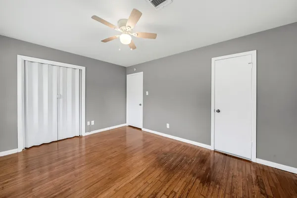 an empty room with wooden floor and windows