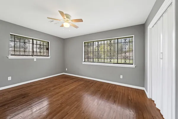 a view of an empty room with wooden floor and a window