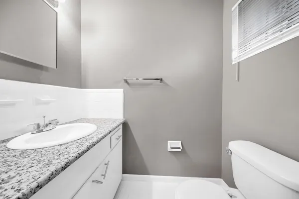 a bathroom with a granite countertop sink toilet and a mirror