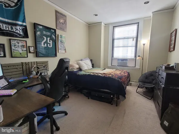 a bedroom with a bed a computer on the desk and chair
