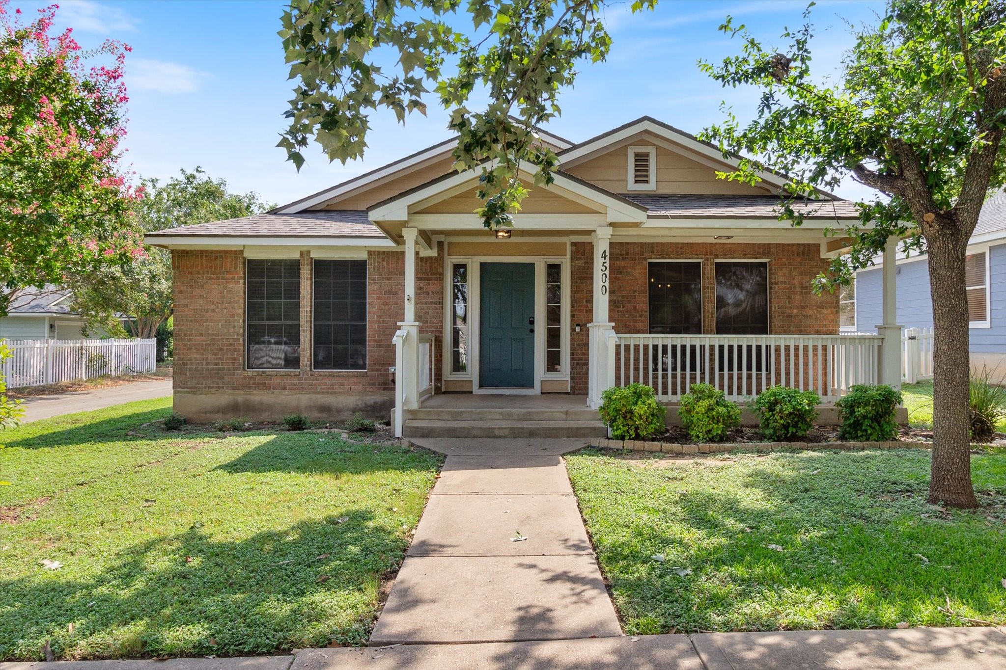 a front view of a house with a yard and potted plants