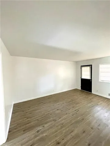 a view of an empty room with wooden floor and windows