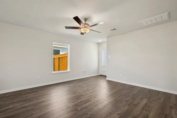 an empty room with wooden floor ceiling fan and windows