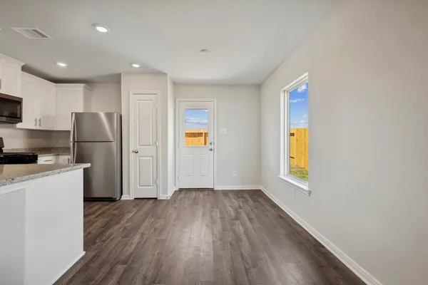 a view of kitchen with a refrigerator a stove top oven and a wooden floor