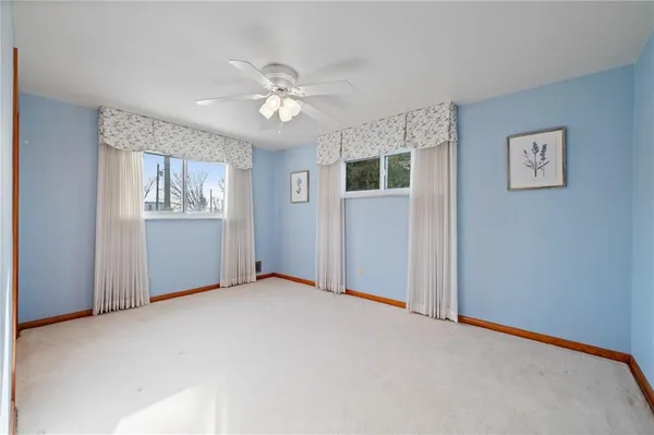 an empty room with a chandelier fan and windows