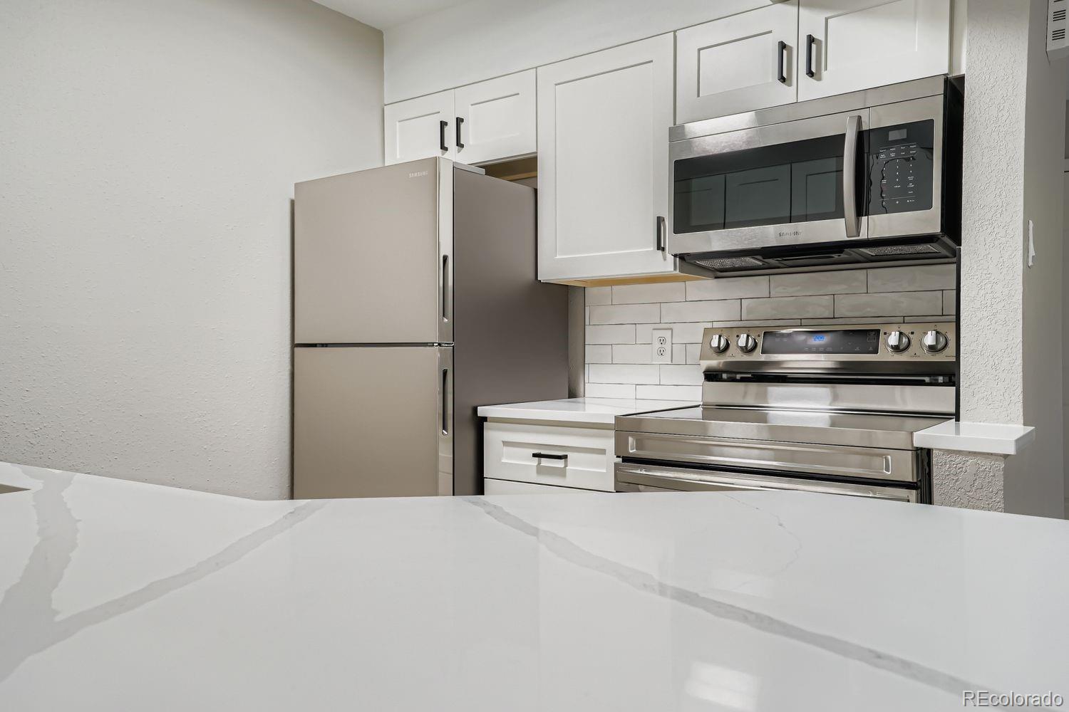 3050 West 32nd Avenue, Unit 102C Denver, CO 80211 - Photo 12 of 36 a kitchen with stainless steel appliances a refrigerator stove and microwave