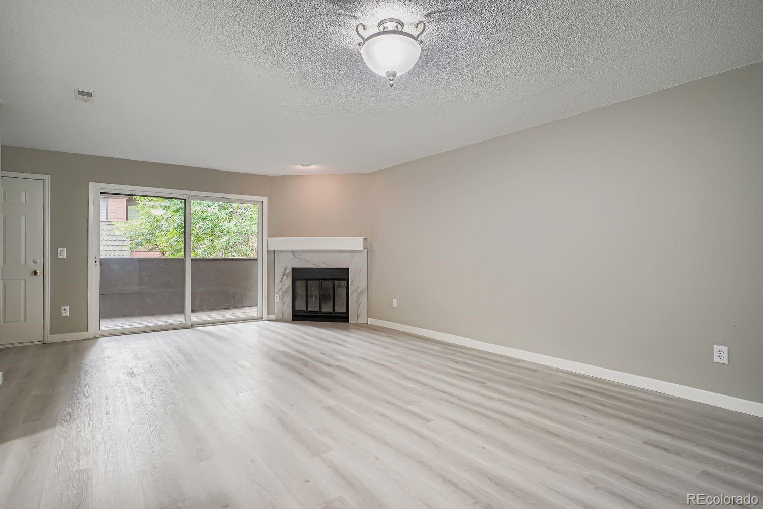 3050 West 32nd Avenue, Unit 102C Denver, CO 80211 - Photo 5 of 36 an empty room with wooden floor fireplace and windows
