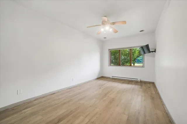 an empty room with wooden floor fan and windows