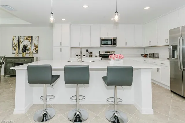 a kitchen with stainless steel appliances kitchen island granite countertop a table chairs and a refrigerator