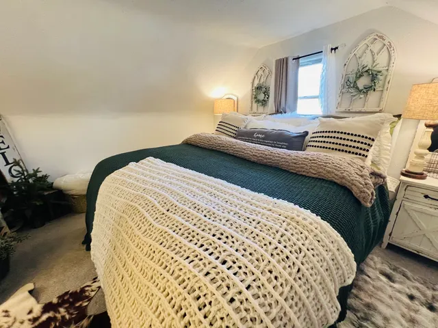 a bedroom with a bed and a lamp on dresser