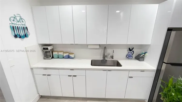 a kitchen with white cabinets and sink