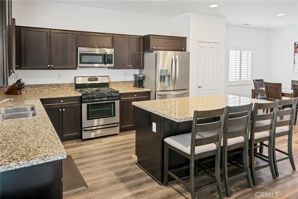 a kitchen with stainless steel appliances granite countertop a stove a sink a microwave a refrigerator and chairs