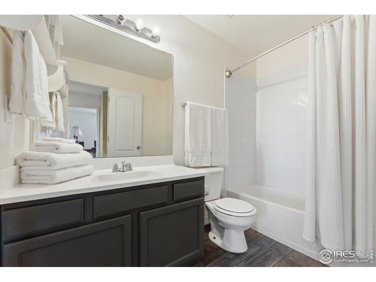 930 Button Rock Drive, Unit 64 Longmont, CO 80504 - Photo 18 of 23 a bathroom with a sink a toilet a large mirror and shower curtain