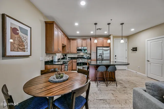 a kitchen with stainless steel appliances granite countertop a sink a stove a refrigerator cabinets and chairs