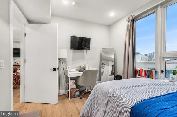 a bedroom with a bed a flat screen tv and a large window