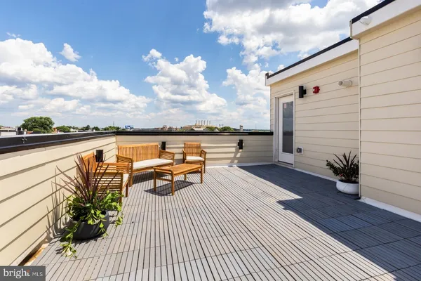 a roof deck with couple of chairs and a potted plant