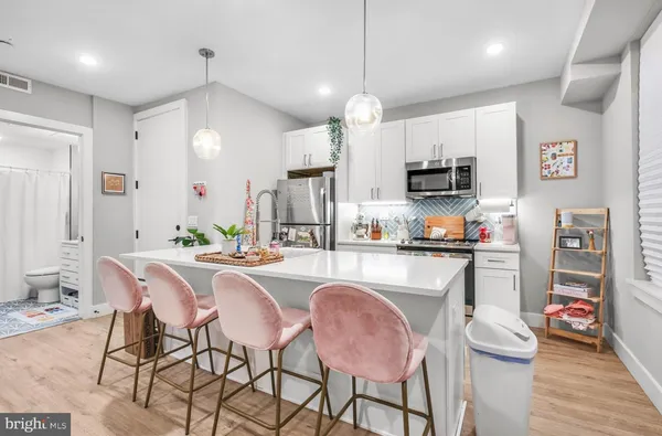 a kitchen with stainless steel appliances a dining table chairs refrigerator and microwave