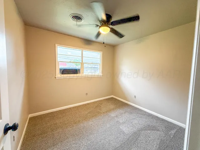 an empty room with a window and a fan