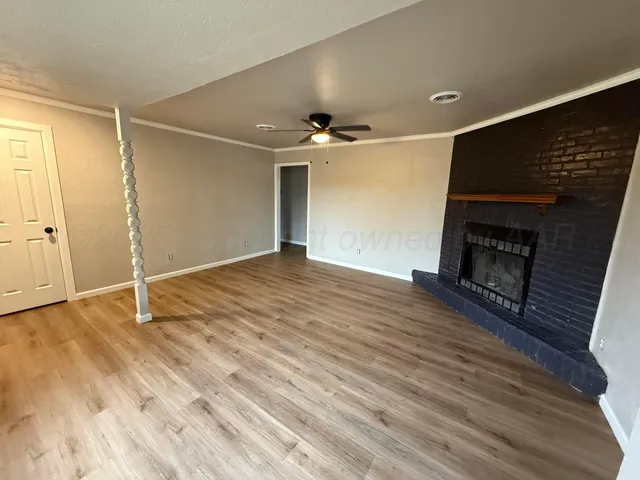 an empty room with wooden floor fireplace and windows