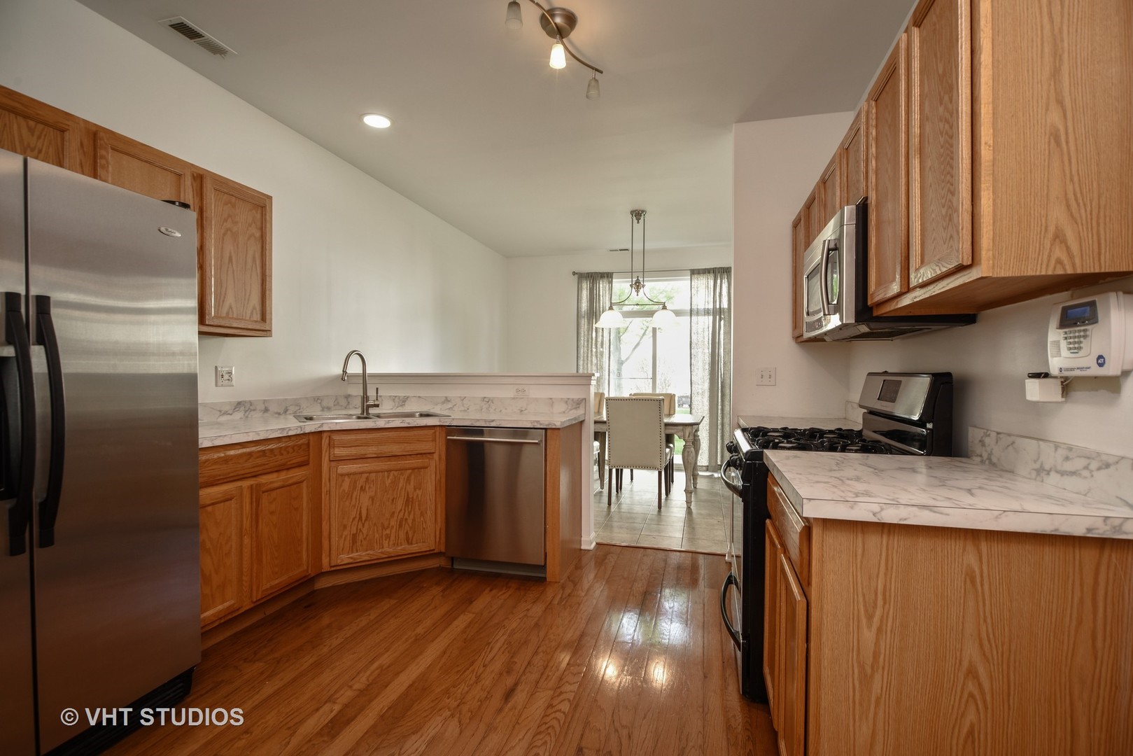2946 Falling Waters Lane Lindenhurst, IL 60046 - Photo 3 of 10 a kitchen with stainless steel appliances granite countertop a sink a stove a refrigerator cabinets and living room view