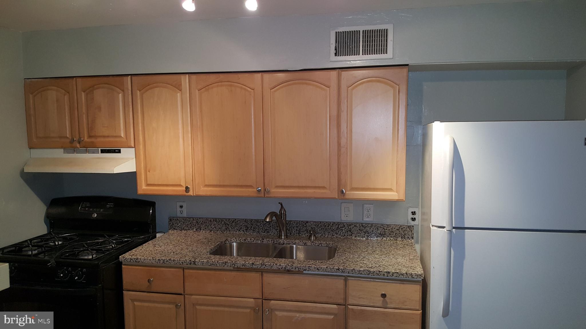 624 Stirling Street Baltimore, MD 21202 - Photo 18 of 27 a kitchen with granite countertop a refrigerator sink and cabinets