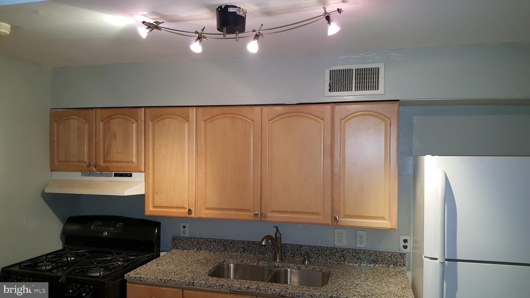 624 Stirling Street Baltimore, MD 21202 - Photo 25 of 27 a kitchen with stainless steel appliances a refrigerator a sink and white cabinets